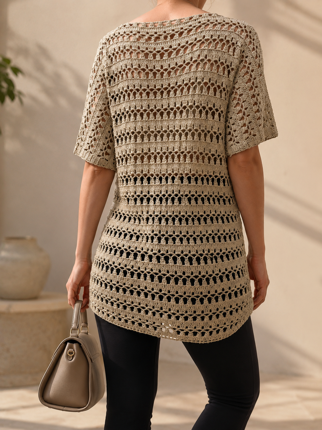Back view of the taupe-grey openwork crochet tunic showing the repeating textured rows and softly curved hem.