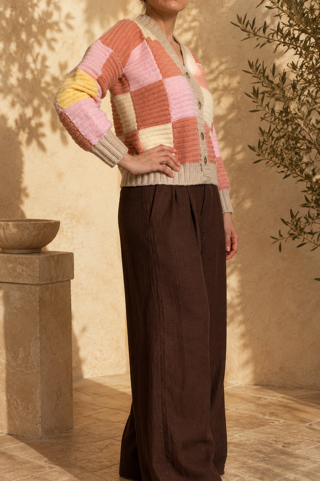 Three-quarter back view of the patchwork crochet cardigan highlighting its dropped shoulders and colour-block construction.