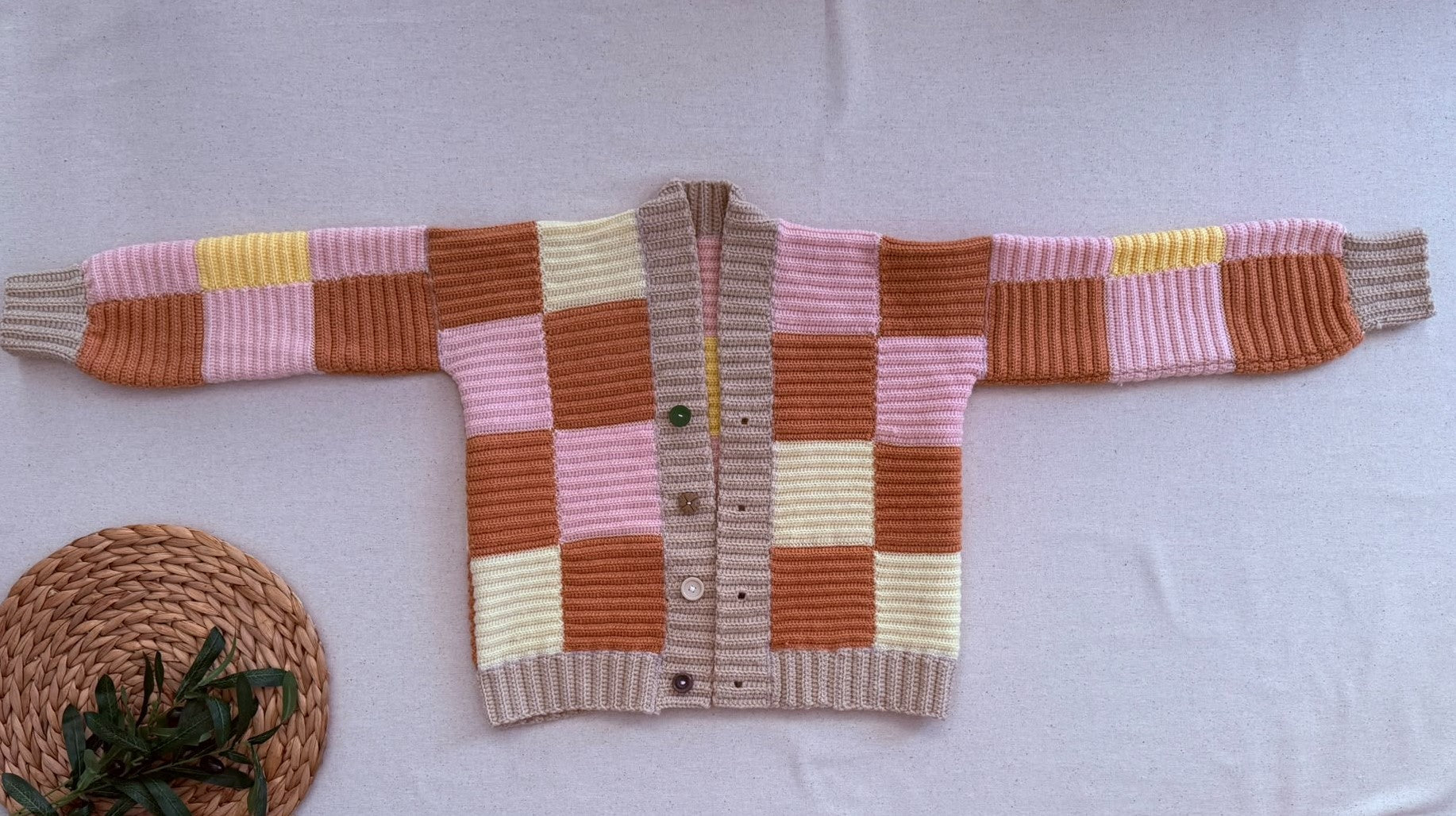 Full flat-lay view of the handmade patchwork crochet cardigan showing its long sleeves, front placket, four buttons and overall proportions.