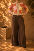 Front view of the handmade patchwork crochet cardigan styled with dark wide-leg trousers, showing its V-shaped opening and four-button front.
