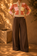 Front view of the handmade patchwork crochet cardigan styled with dark wide-leg trousers, showing its V-shaped opening and four-button front.