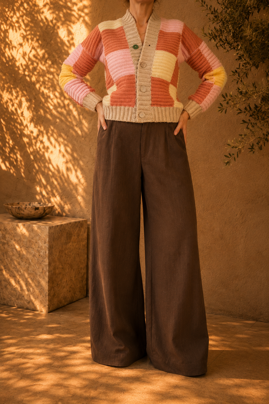 Front view of the handmade patchwork crochet cardigan styled with dark wide-leg trousers, showing its V-shaped opening and four-button front.