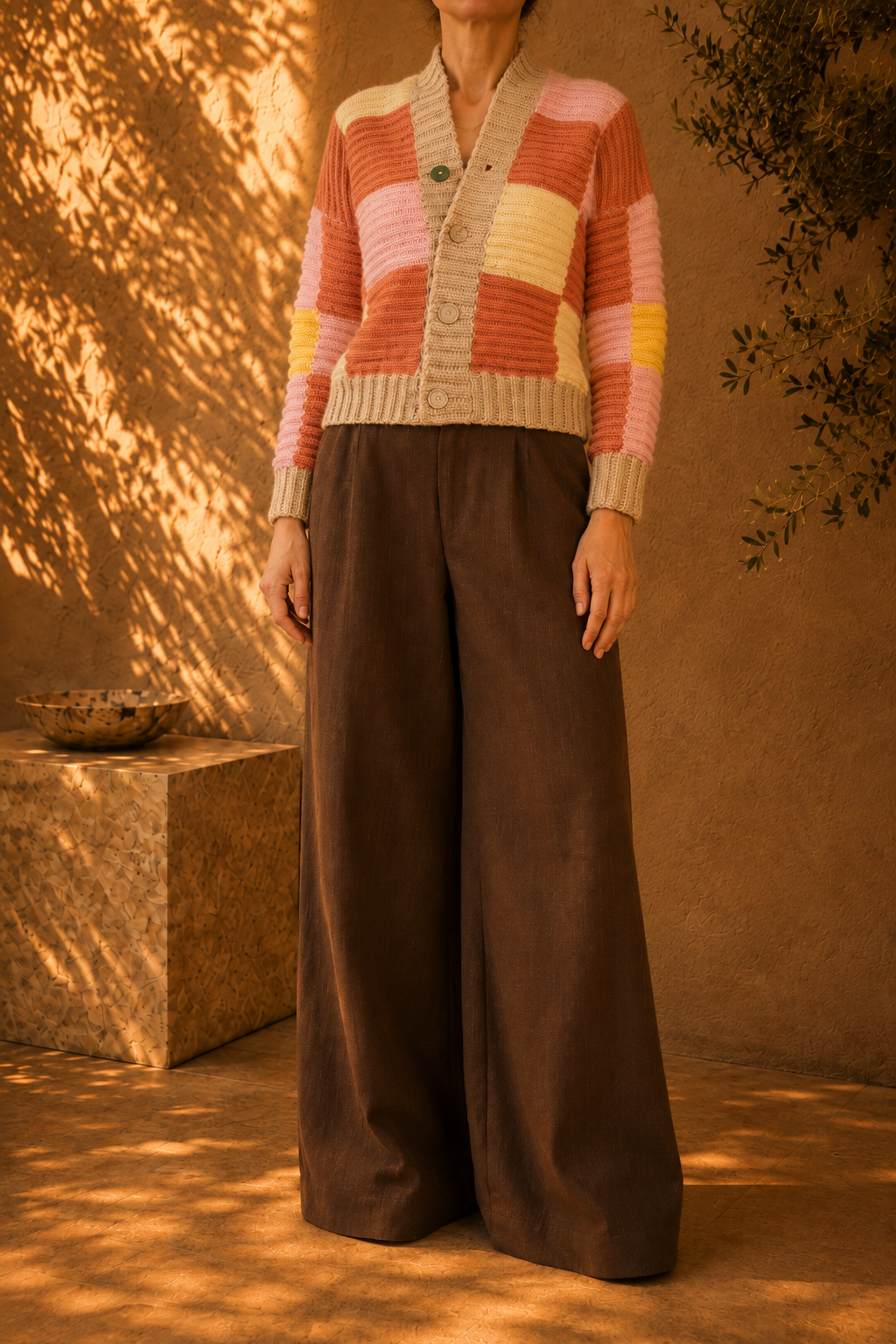 Three-quarter side view of the multicolour crochet cardigan showing its relaxed silhouette, long sleeves and patchwork colour blocks.