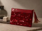 Front view of the handmade red sequin clutch bag with patent leather tassel and gold-tone frame.