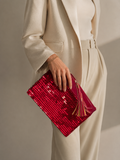 Handmade red sequin clutch bag held by hand, shown from the front with patent leather tassel detail.