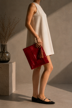 Woman carrying the handmade red sequin clutch bag by hand, shown from the side.
