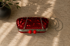 Top view of the handmade red sequin clutch showing the metal frame, clasp balls, sequined exterior and chain strap.