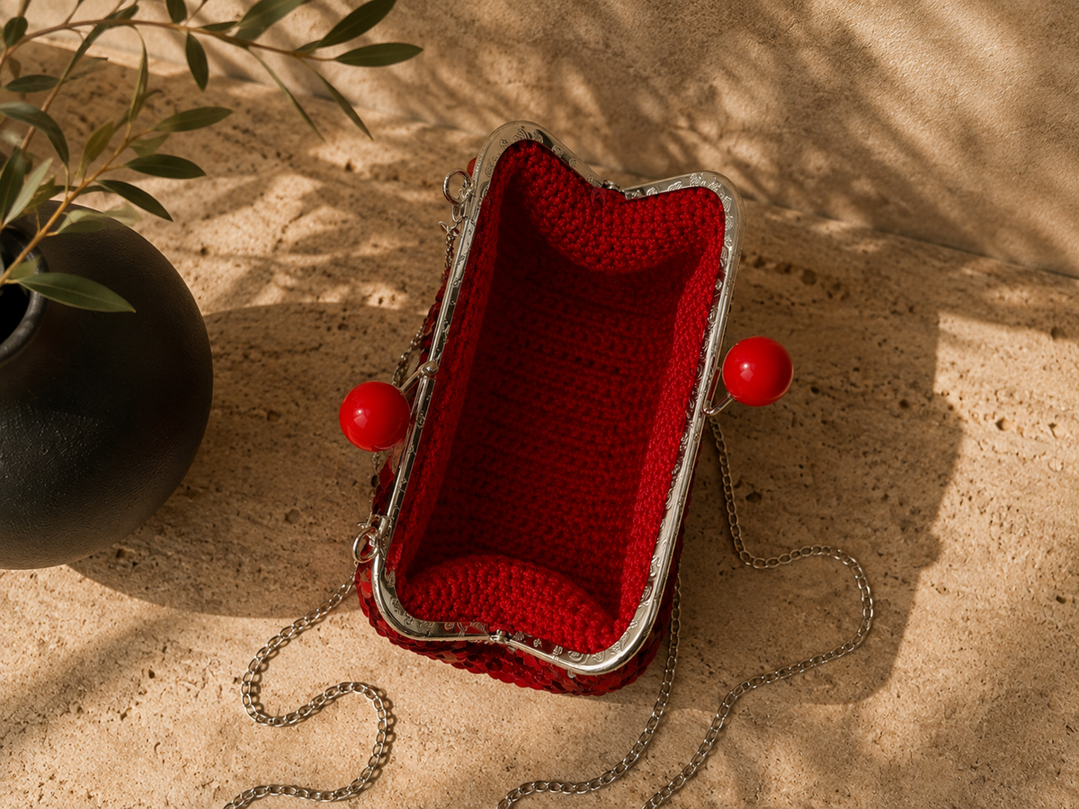 Open view of the red sequin clutch bag showing its kiss-lock frame and unlined handmade crochet interior.