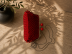 Side profile of the red sequin evening bag showing its structured depth, rounded body and hard plastic clasp balls.