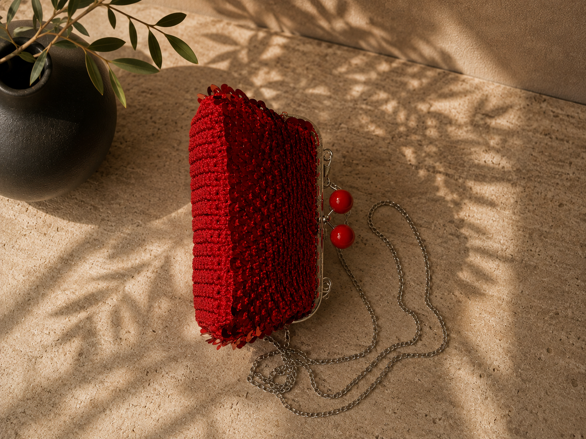 Side profile of the red sequin evening bag showing its structured depth, rounded body and hard plastic clasp balls.