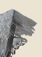 Detailed view of the naturally draped outer edge of the handmade round crochet lace table topper.