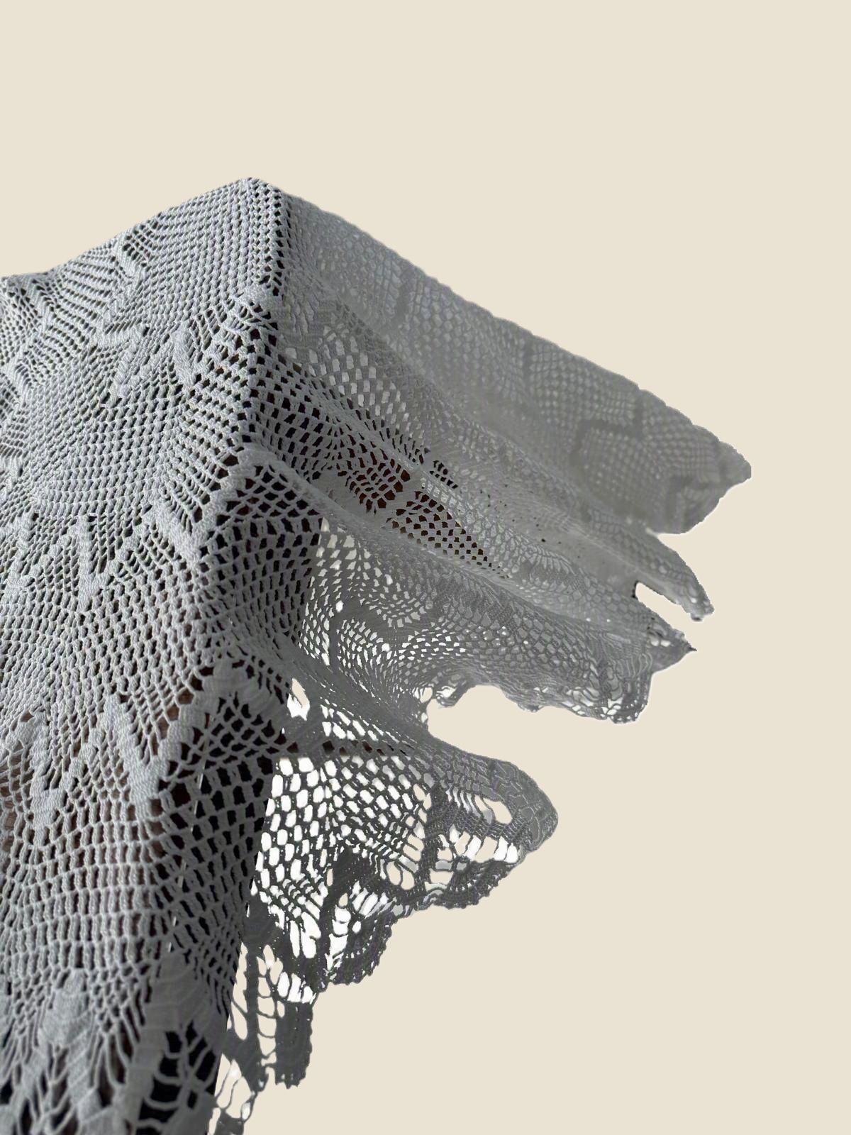 Detailed view of the naturally draped outer edge of the handmade round crochet lace table topper.