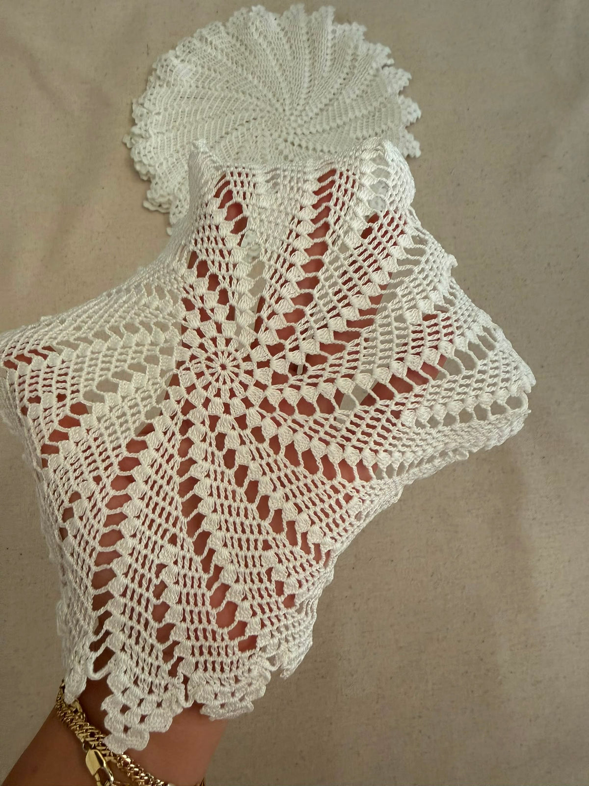 Handheld view of the 23 cm white round crochet lace motif showing its real scale and pointed edge.