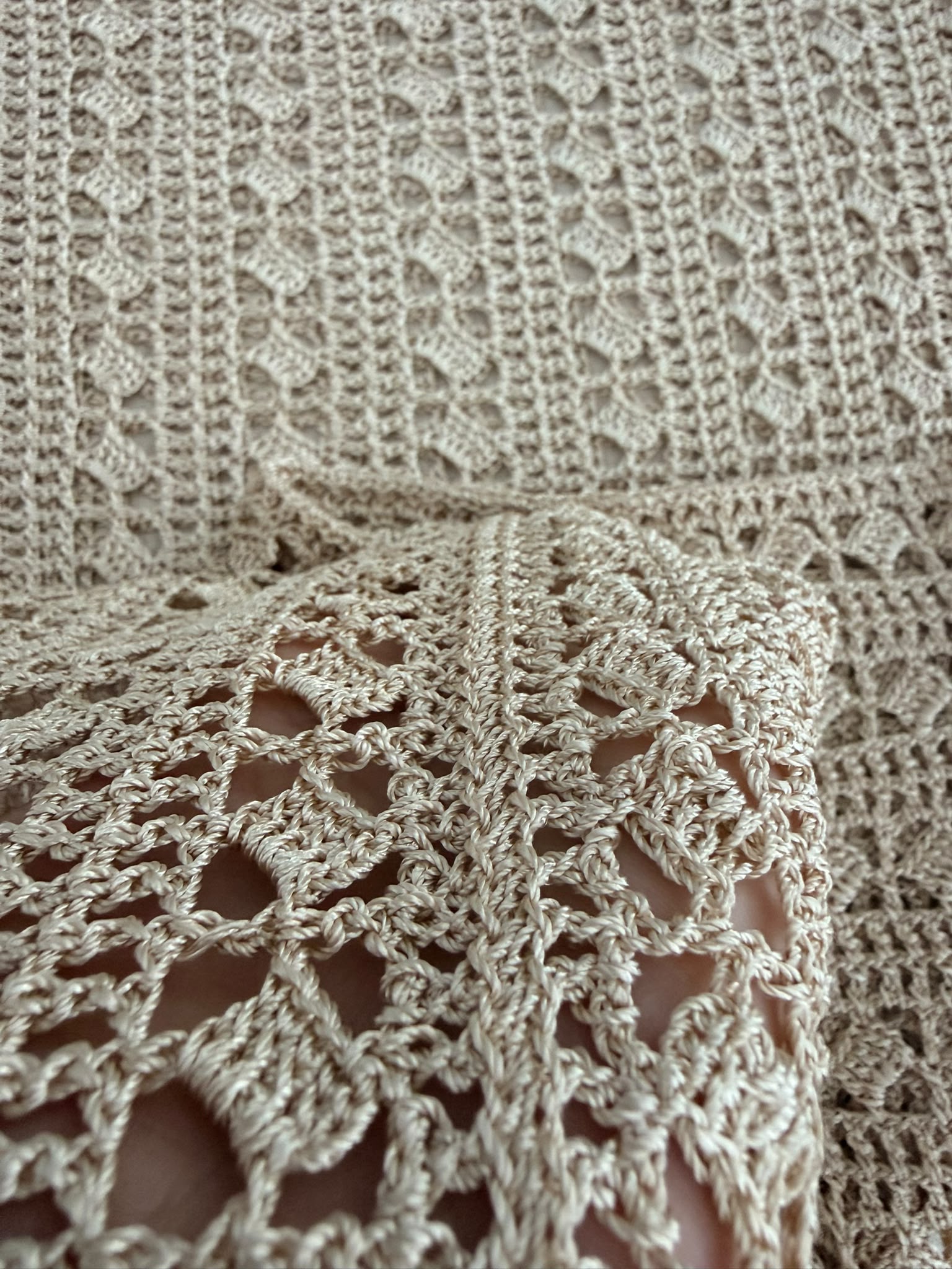 Close-up of the sand-beige crochet fabric showing alternating openwork and more closely worked stitch rows.