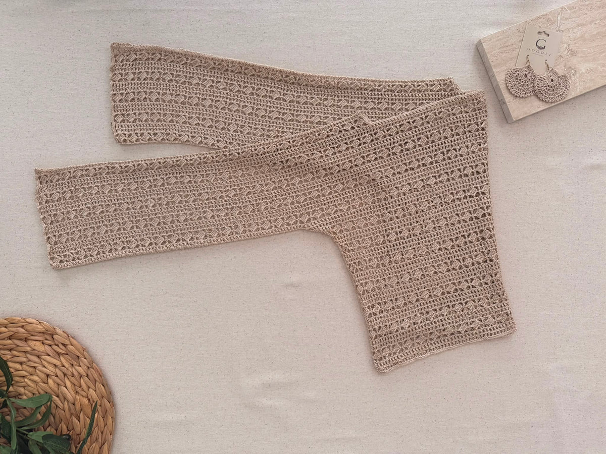 Full flat-lay view of the long-sleeve crochet blouse showing its straight shoulder construction, wide neckline and overall proportions.