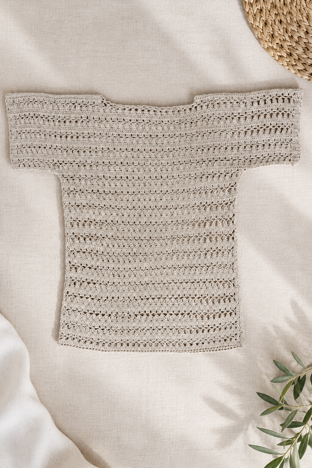 Flat-lay view of the handmade taupe-grey crochet tunic top showing its openwork pattern, short sleeves and longline shape.