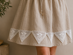 Styling example showing repeated white triangular crochet lace motifs decorating the hem of a neutral skirt.