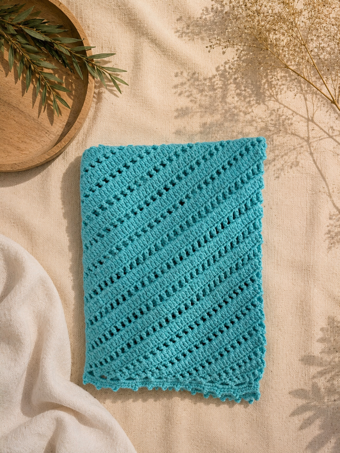 Detailed flat view of the turquoise crochet fabric showing alternating openwork rows and diagonal stitch direction.