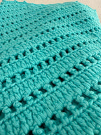 Close-up of the turquoise crochet top showing the premium micro acrylic yarn, clear stitch definition and openwork texture.