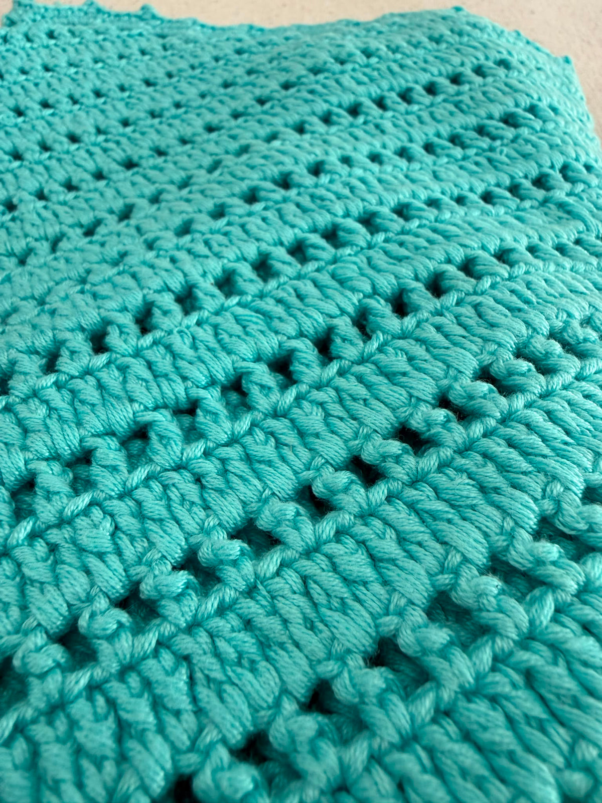 Close-up of the turquoise crochet top showing the premium micro acrylic yarn, clear stitch definition and openwork texture.