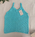 Full flat-lay view of the handmade turquoise crochet tank top showing its V-neckline, slim straps and overall shape.