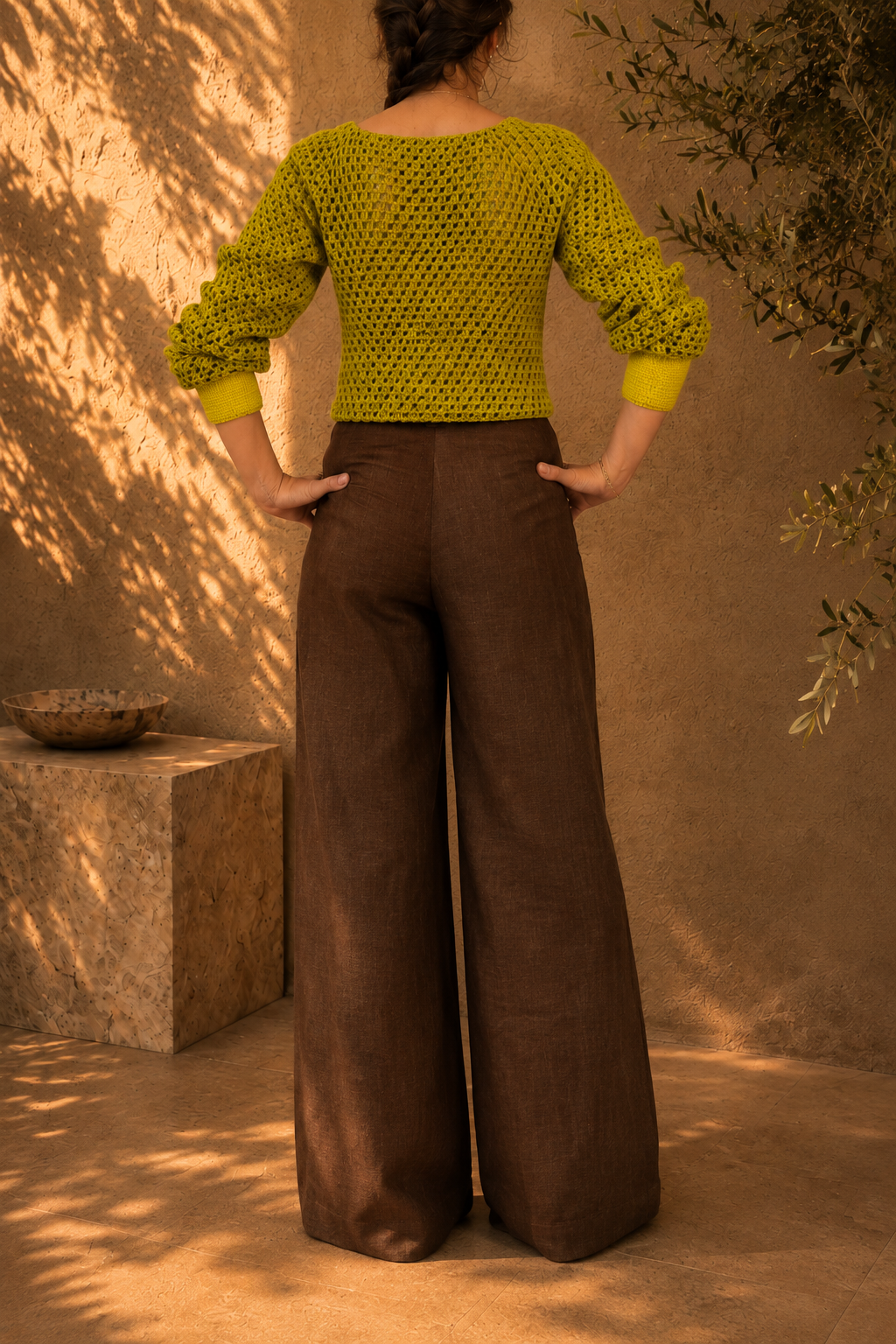 Three-quarter back view of the two-tone crochet jumper highlighting its waist-length shape and contrasting lime green yellow hem.
