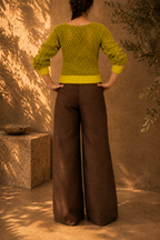 Back view of the handmade green yellow crochet jumper showing the continuous openwork stitch pattern across the body and long sleeves.