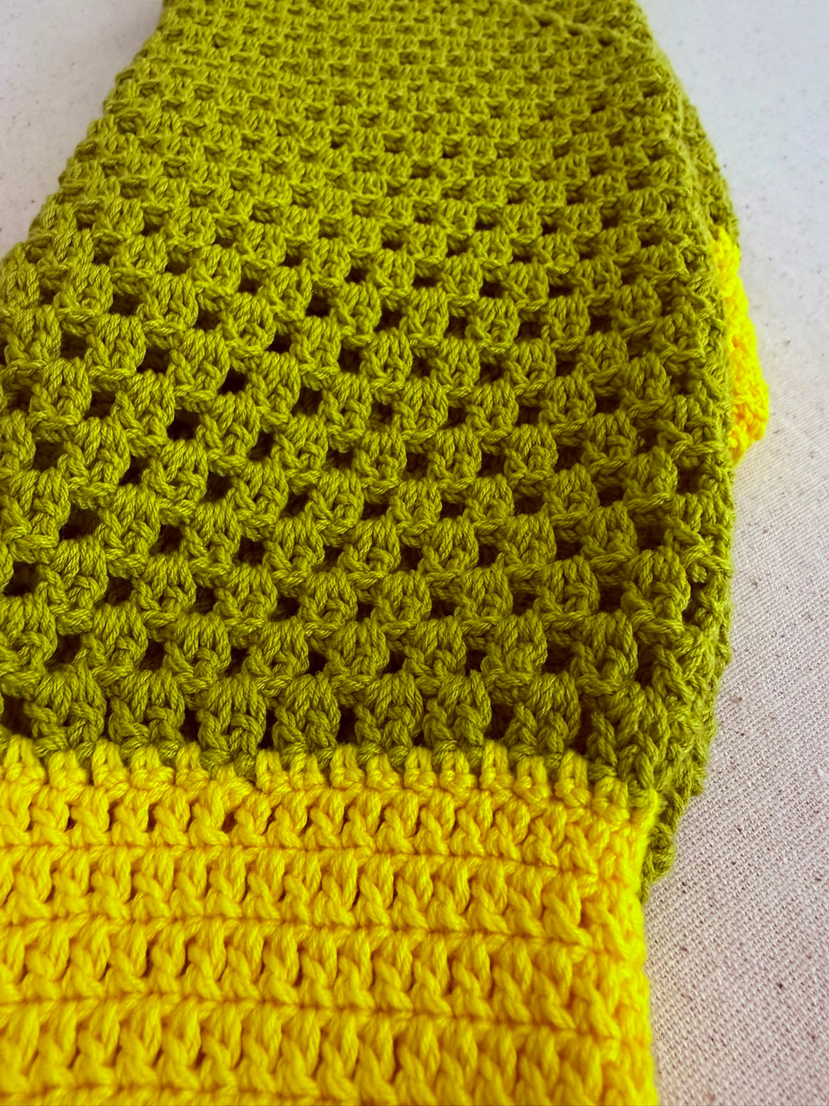 Close-up of the green crochet jumper showing the transition between the openwork sleeve and the denser lime green cuff.