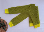 Folded view of the green crochet jumper showing its crossed long sleeves, open stitch texture and bright lime cuffs.