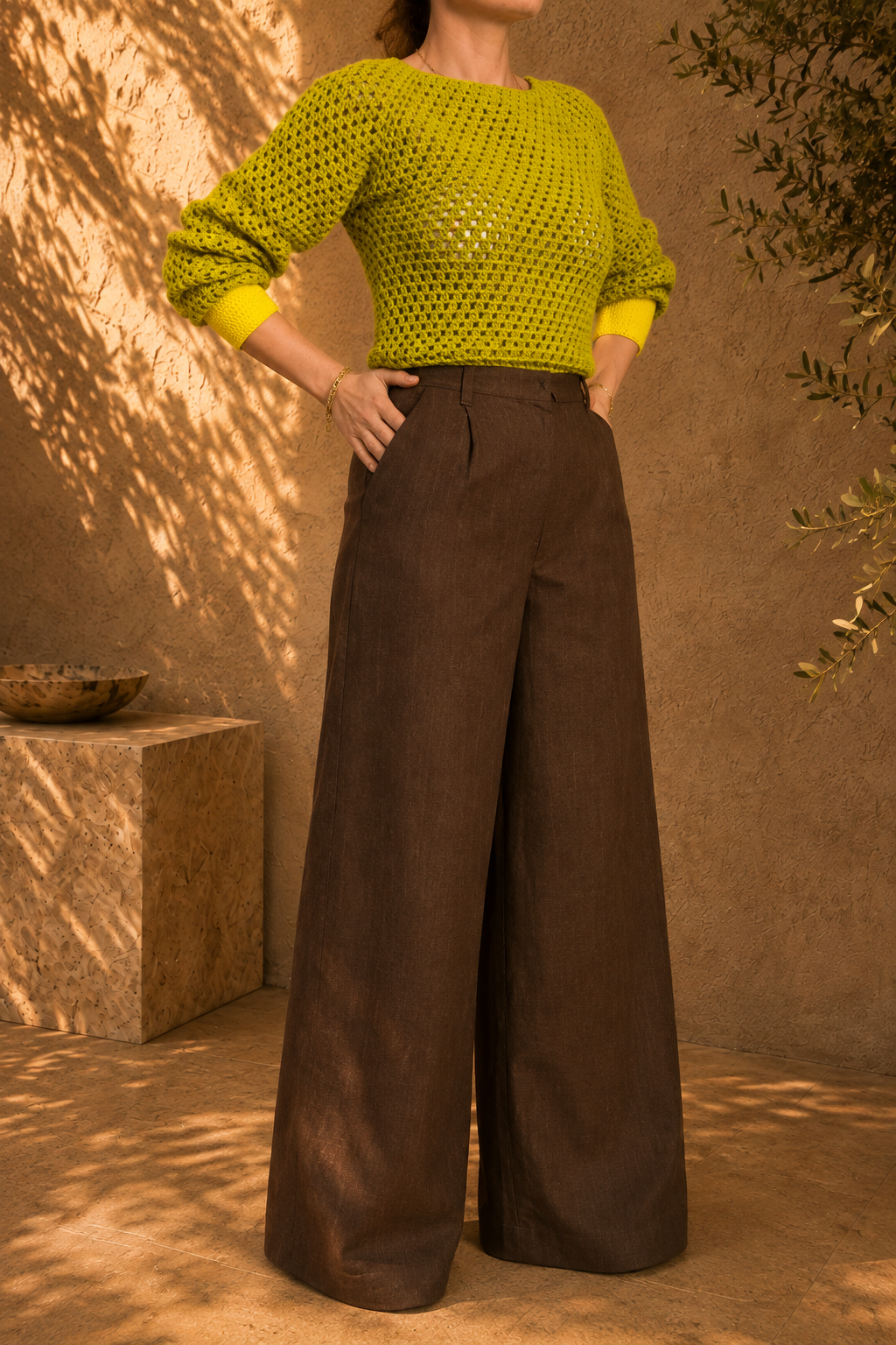 Full-length front view of the two-tone green yellow crochet jumper showing its long sleeves, openwork body and contrasting cuffs and hem.