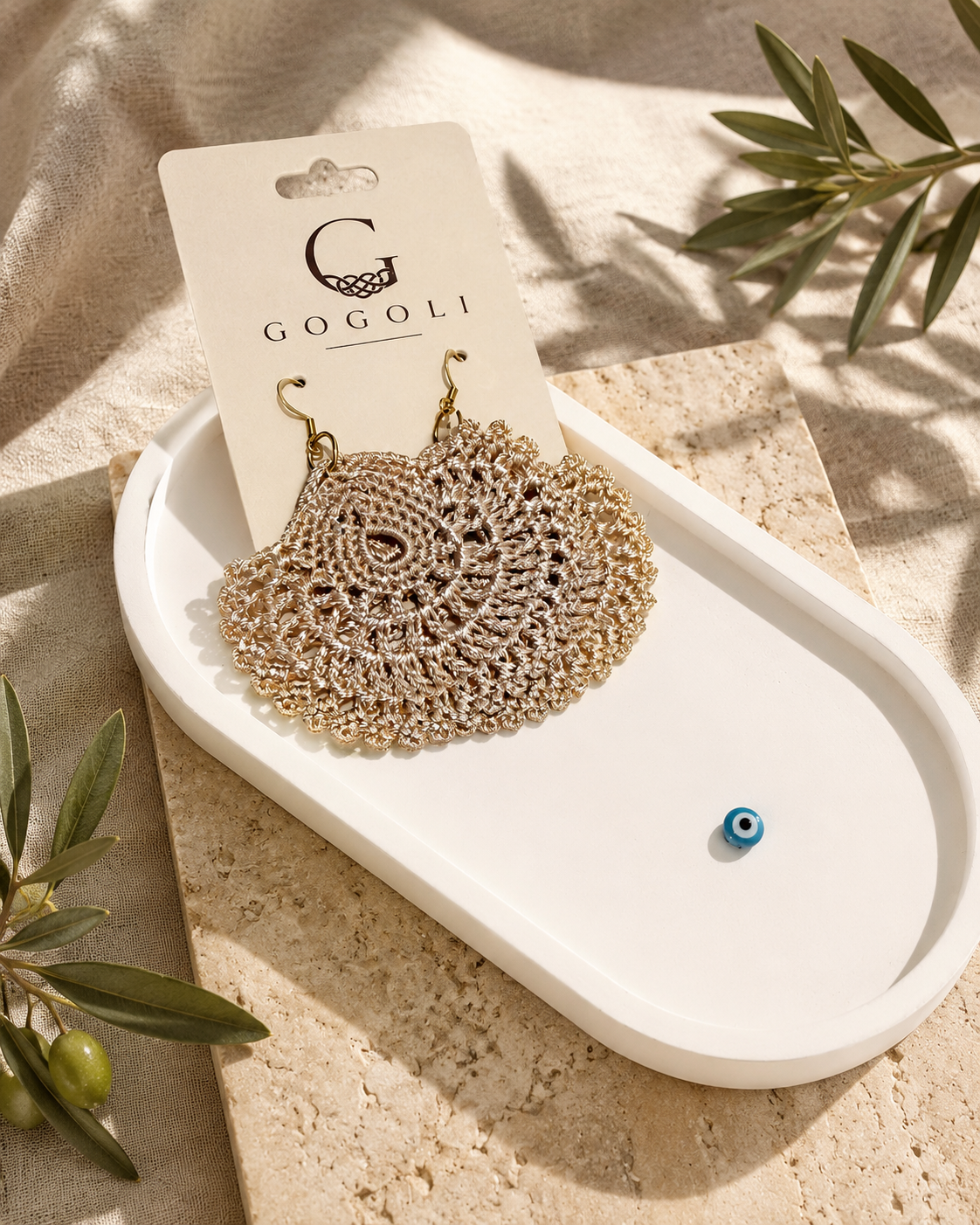 Warm sand-beige crochet earring presented beside a GOGOLI jewellery card on a white decorative tray.