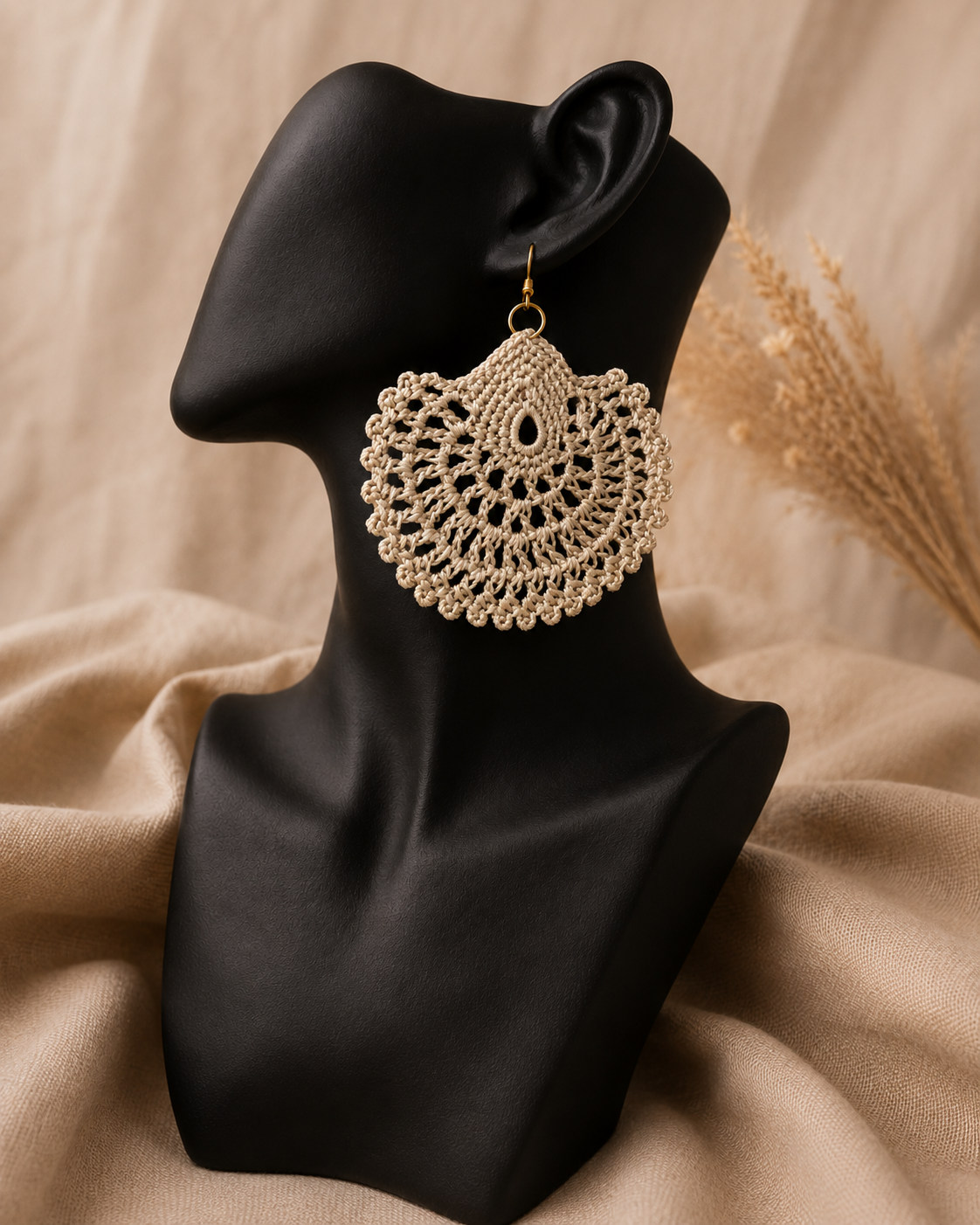 Warm sand-beige round crochet statement earring displayed on a black jewellery bust with a gold-tone stainless steel hook.