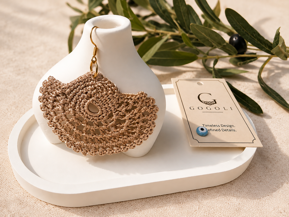 Pair of warm sand-beige crochet earrings styled on a white jewellery display with GOGOLI packaging.