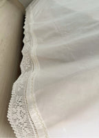 Detail of the white cotton fabric, handmade crochet lace and decorative piko-sarma finished edge.