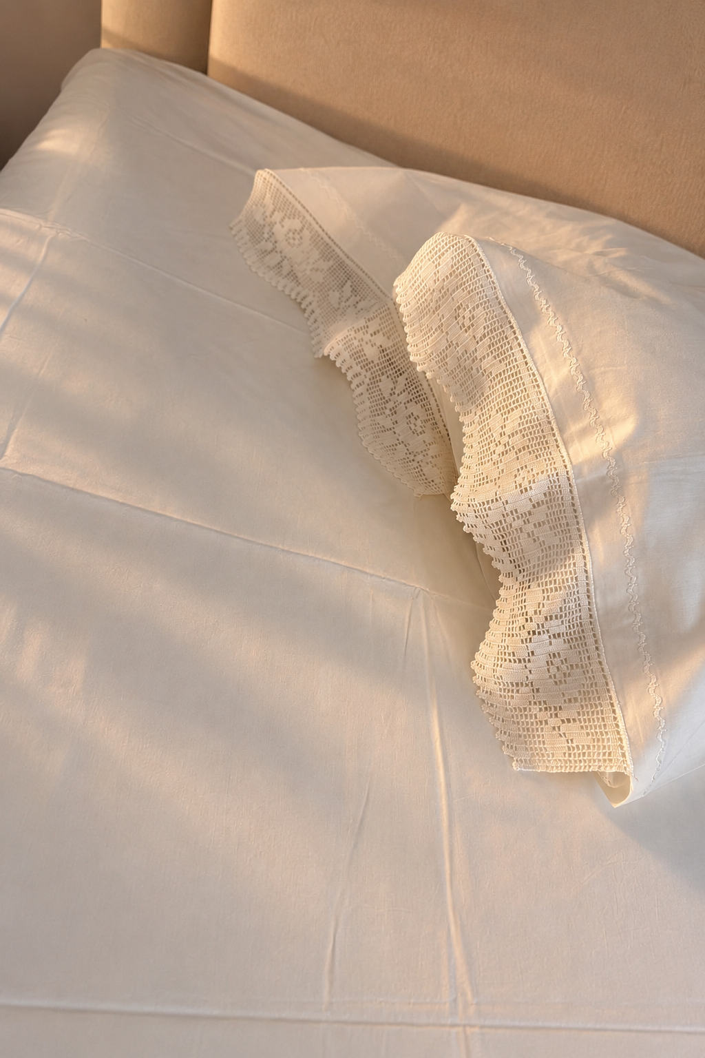 Close view of the white cotton bed sheet showing the handmade crochet lace applied along the finished edge.