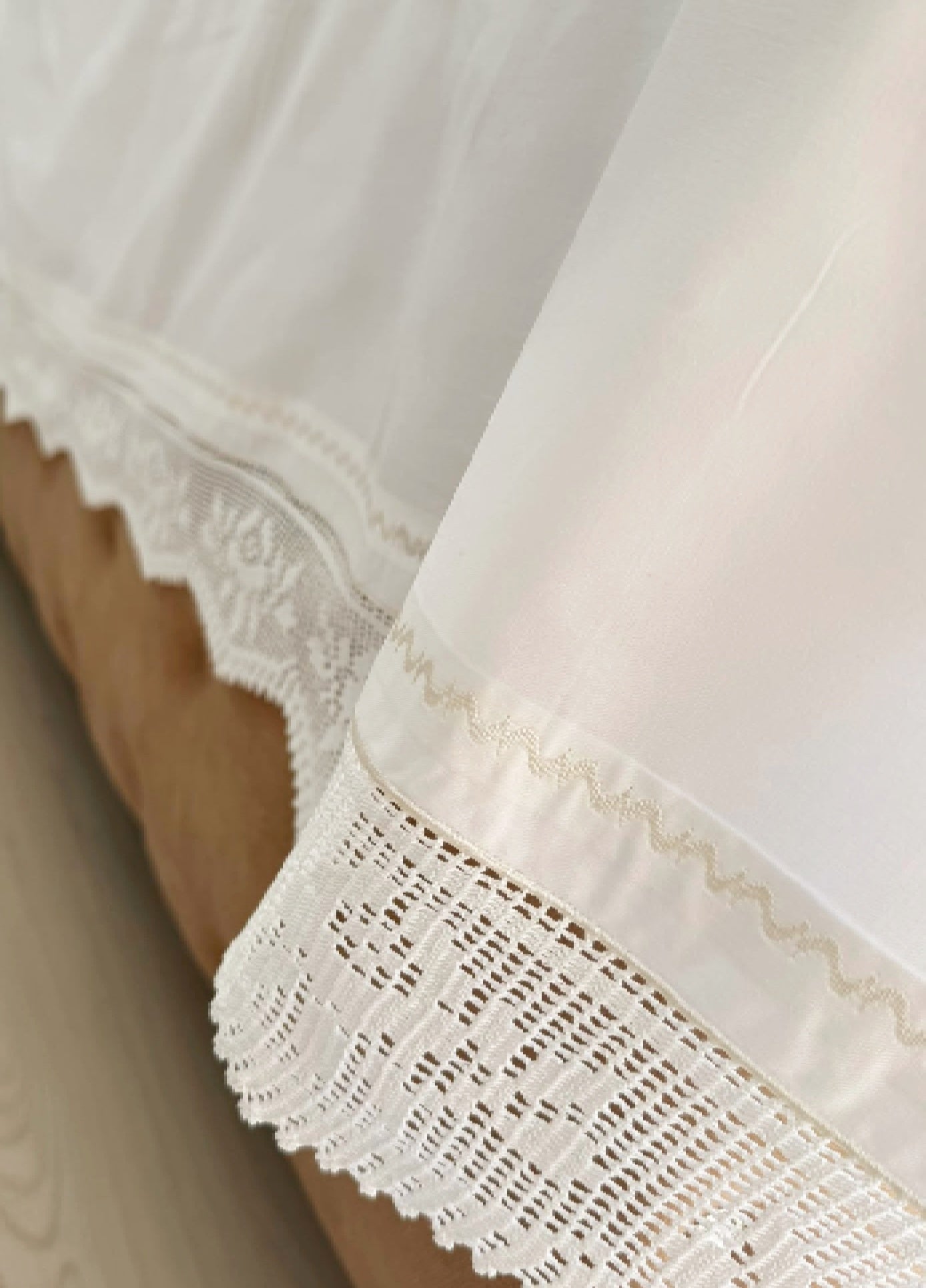 Detail of the white cotton bed sheet showing the crochet lace edge and clean decorative finishing.