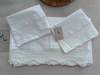 Folded white cotton bed linen set showing the crochet lace edging and coordinated three-piece construction.