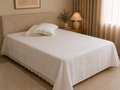 White cotton bed linen set styled on a bed, showing the crochet lace edging on the sheet and matching pillowcases.
