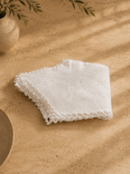 Folded detail view of the handmade white cotton table cover showing the layered crochet edges and stitch structure.