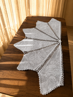 Side view of the white cotton crochet table cover showing the pointed sections extending across the table surface.