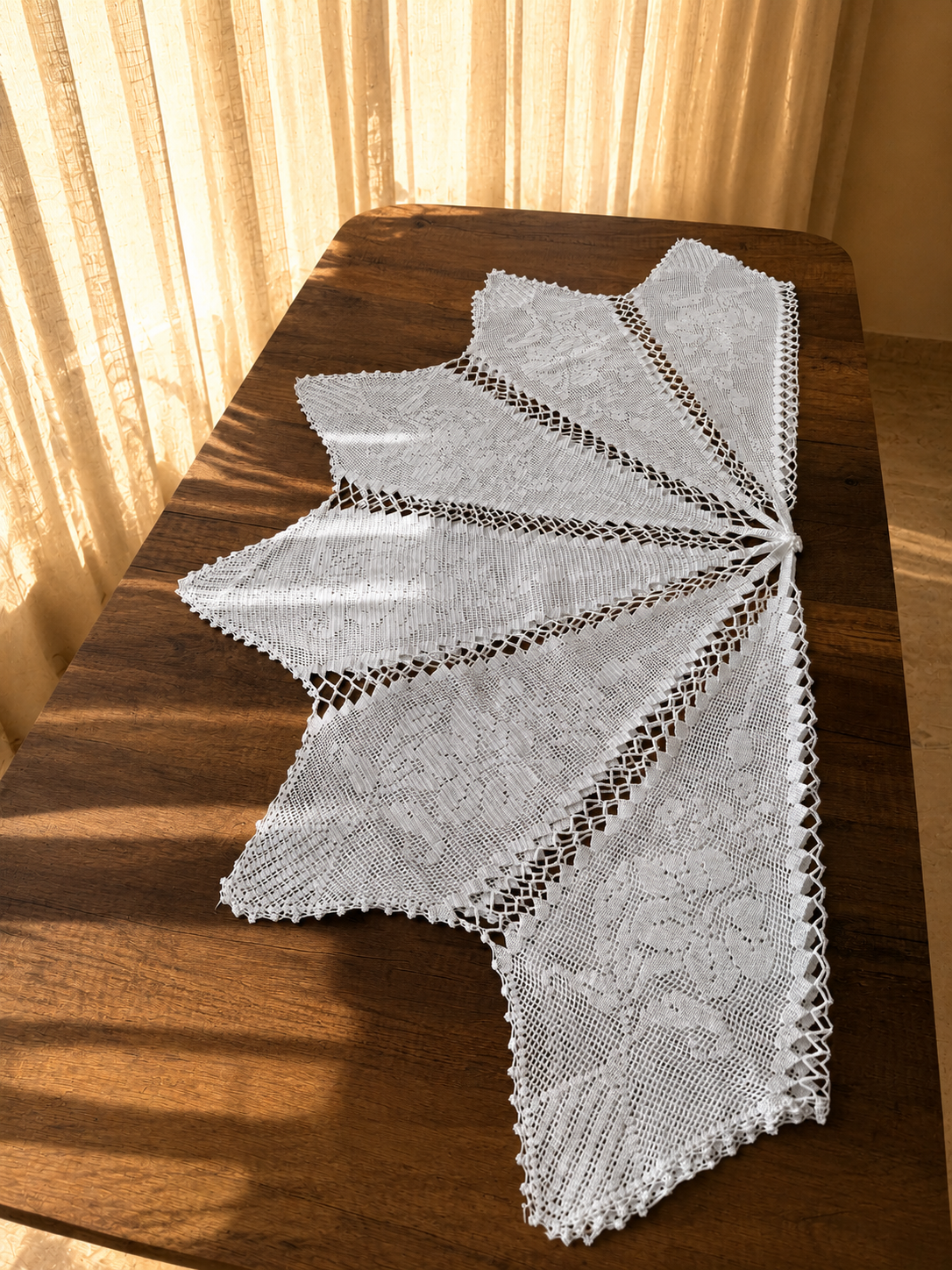 Side view of the white cotton crochet table cover showing the pointed sections extending across the table surface.
