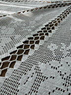 Close-up of the white cotton crochet table cover showing the openwork pattern, joined sections and handmade stitch detail.