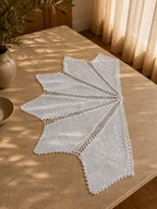 Three-quarter view of the white cotton crochet table cover displaying its openwork pattern and alternating pointed edges.