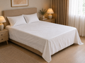 White cotton bed linen set styled on a bed, showing inset handmade crochet lace along the sheet and matching pillowcases.