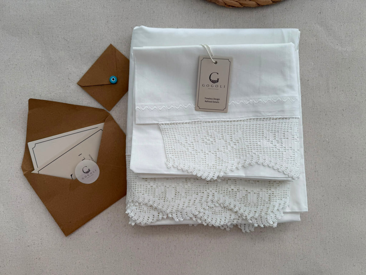 Folded GOGOLI white cotton bed linen set with visible crochet lace detail and presentation card.