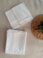 Folded white cotton pillowcases showing the handmade crochet lace placed along the opening edge.