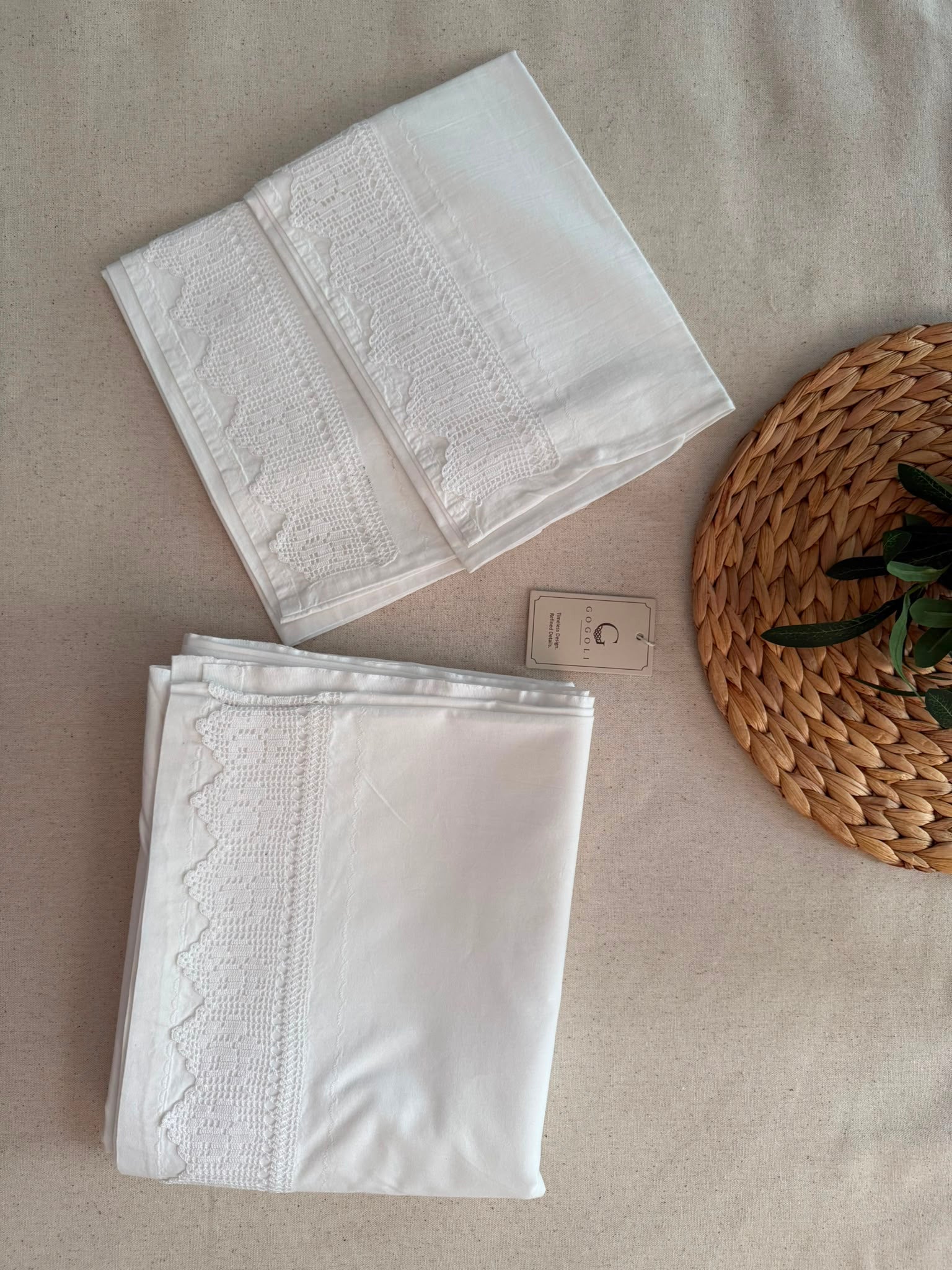 Folded white cotton pillowcases showing the handmade crochet lace placed along the opening edge.