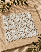 Close-up of a small white crochet doily showing its floral motifs and handmade cotton thread texture.