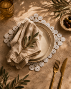 A handmade white crochet lace doily set—featuring alternating floral motifs, circular medallions, and openwork lace craftsmanship—displayed as charger plate mats.