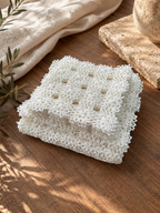 Stacked arrangement of the small square crochet doilies, showing their repeating motifs and handmade lace edges.